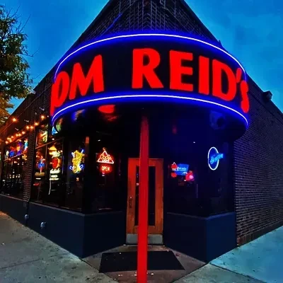 Exterior of Tom Reid's building with vibrant neon signs at night.