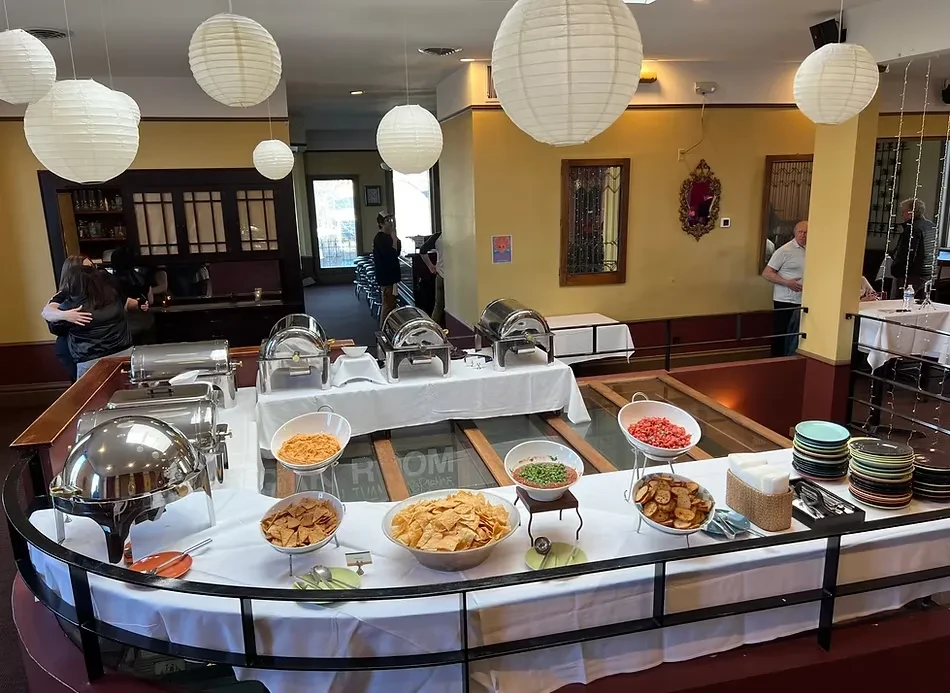 A restaurant buffet table with food, plates, and hanging lanterns.