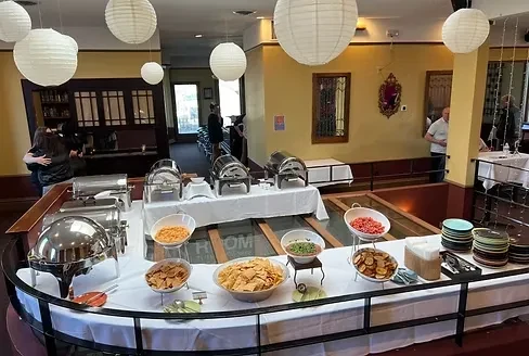 Blurry indoor buffet with chips, salsa, guacamole, and people.