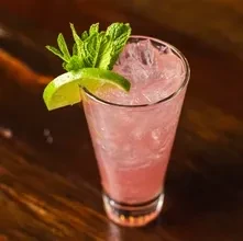 Vibrant pink cocktail with crushed ice, lime, and mint.