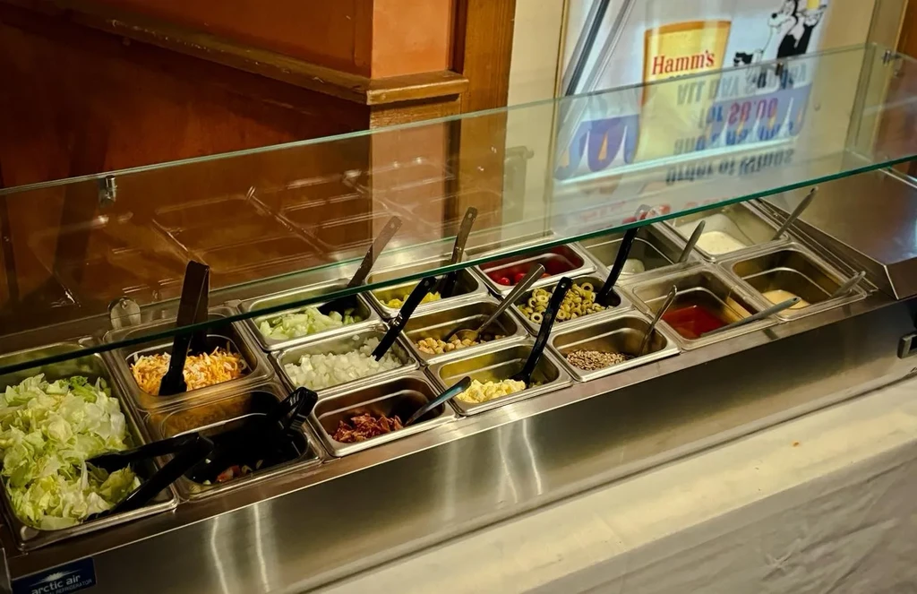 Refrigerated self-service food bar with many salad and topping options.