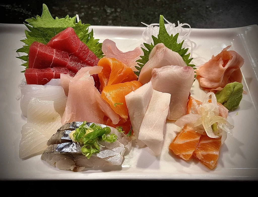 Artfully arranged assorted sashimi platter featuring tuna, salmon, and garnishes.