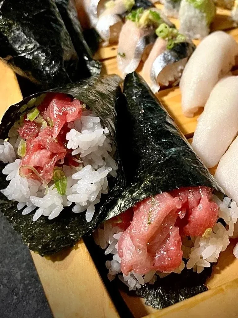 Tuna temaki hand rolls and nigiri sushi on a wooden tray.
