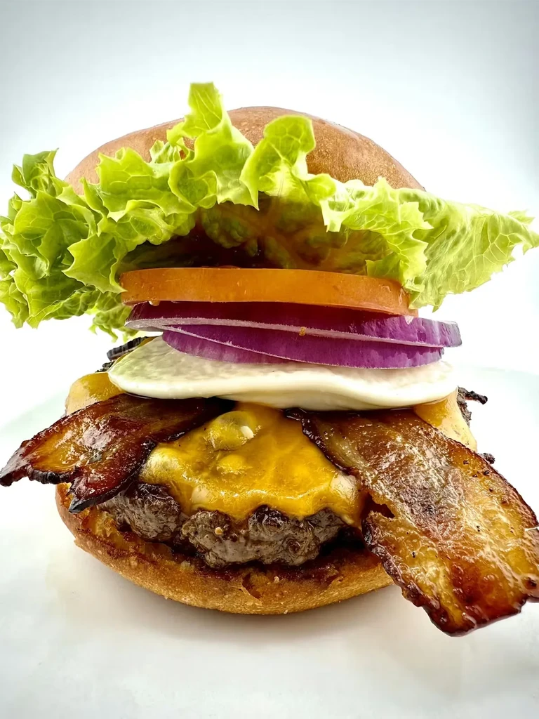 Char-grilled burger with melted cheddar, bacon, fried egg, lettuce, tomato, onion.