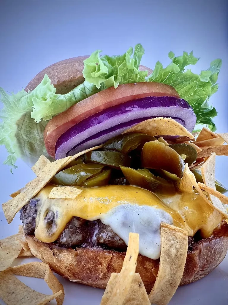 Stacked burger with melted cheese, jalapeños, and crispy tortilla strips.