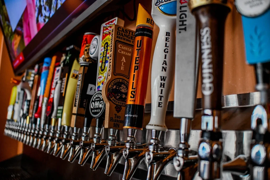 A close-up view of a long row of colorful beer tap handles.