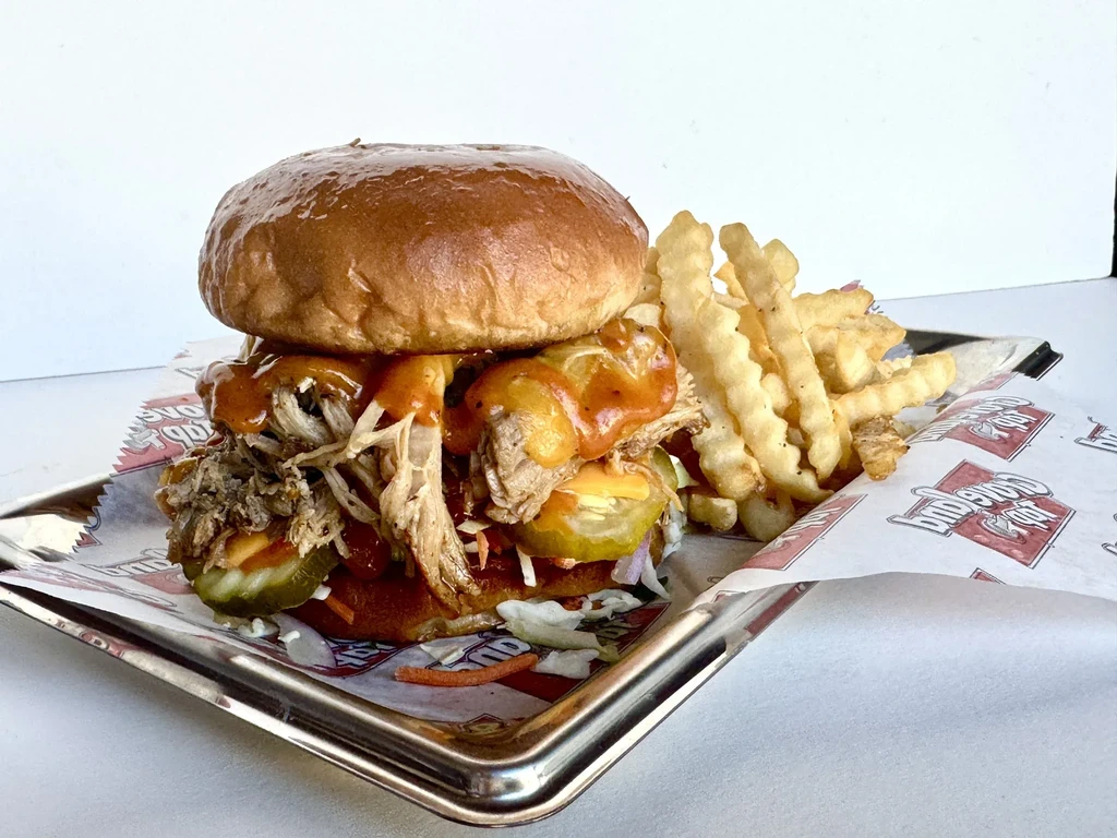 Barbecue sandwich and crinkle-cut fries on a metal tray.