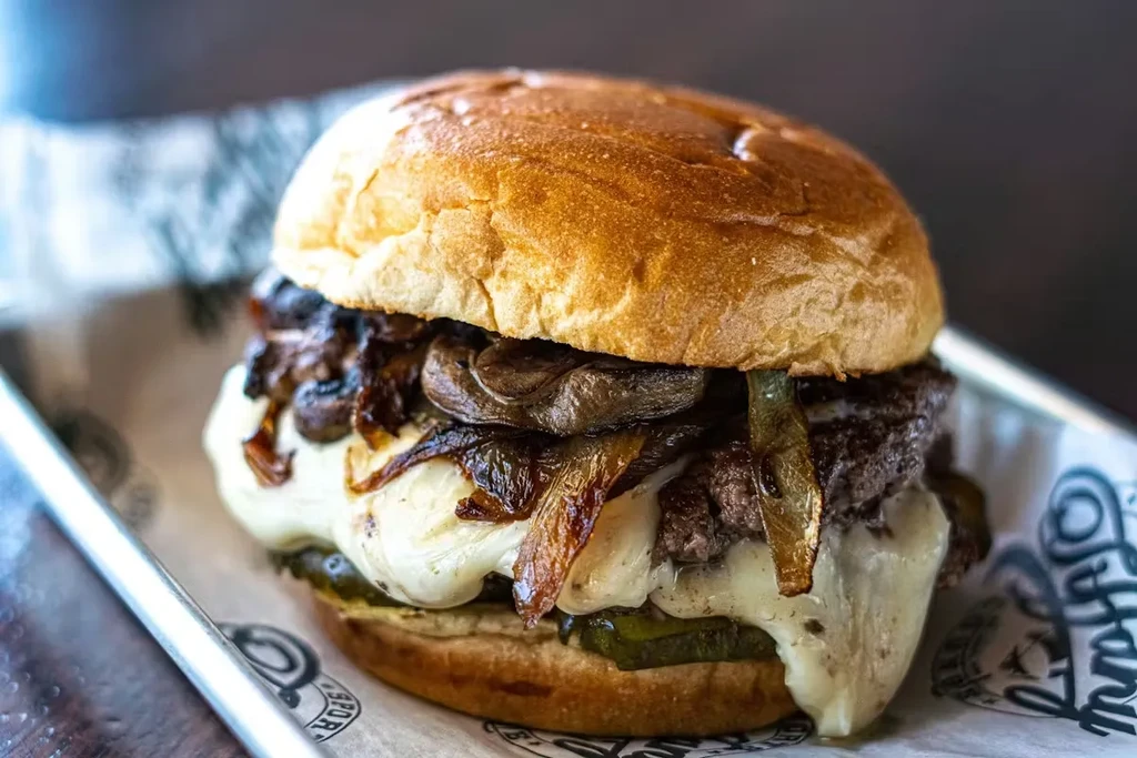 Gourmet burger with melted cheese, mushrooms, and caramelized onions.