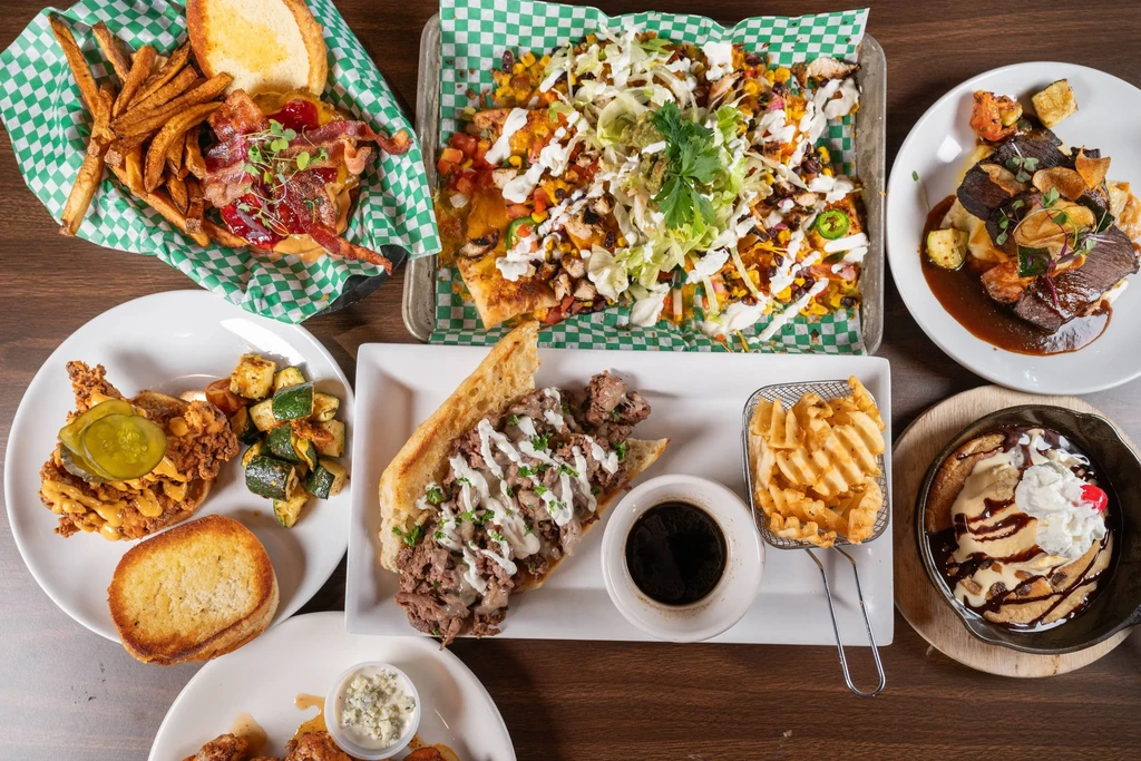 Flat lay of diverse prepared food dishes on a dark wooden table.