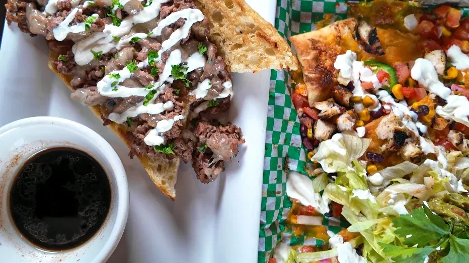 Top-down view of a meat sandwich and loaded chicken nachos.