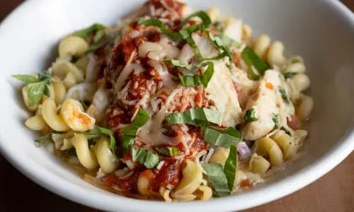 Creamy pasta with chicken, red sauce, melted cheese, and fresh basil.