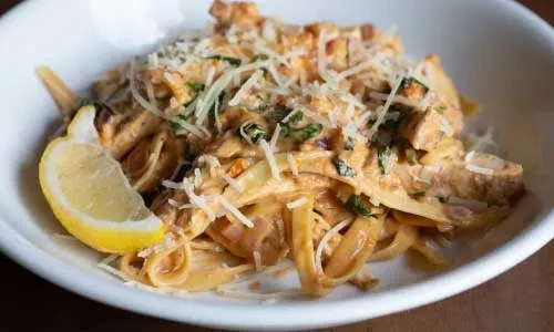 Creamy linguine with chicken, tomato sauce, cheese, herbs, and lemon.