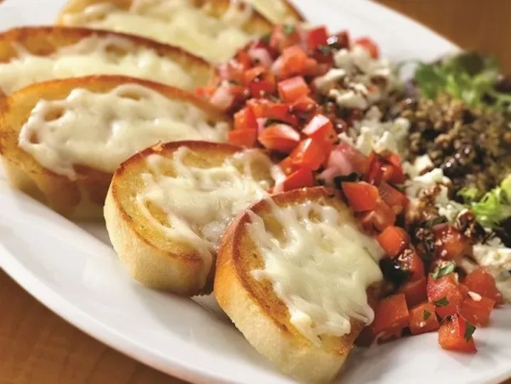 Cheesy bread crostini with tomatoes, feta, and balsamic drizzle.