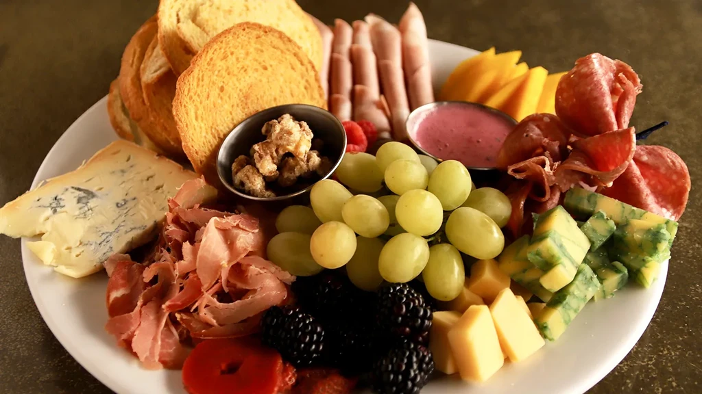 Abundant charcuterie board with diverse cheeses, meats, fruits, and crostini.