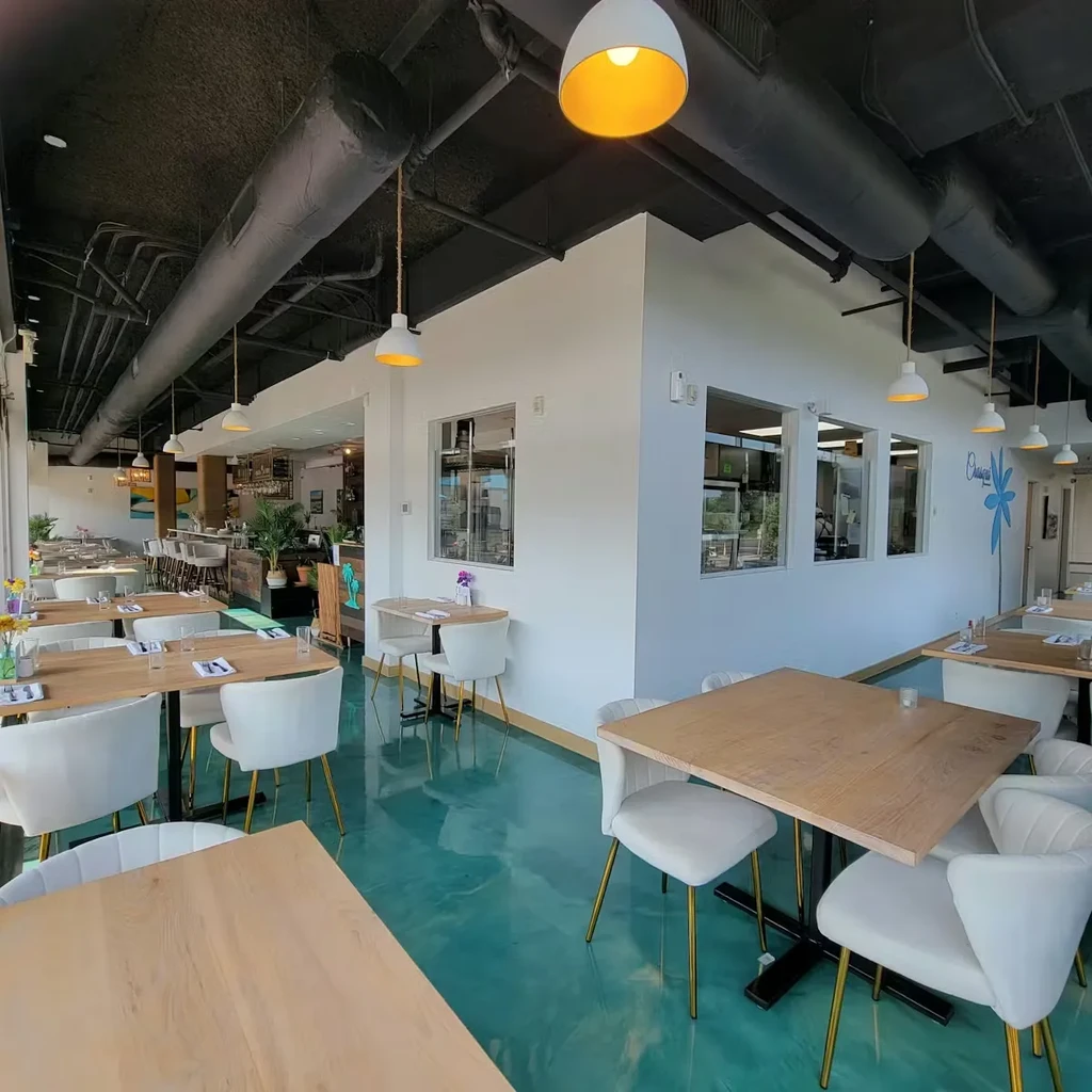Modern restaurant interior with teal floor, white walls, and industrial ceiling.