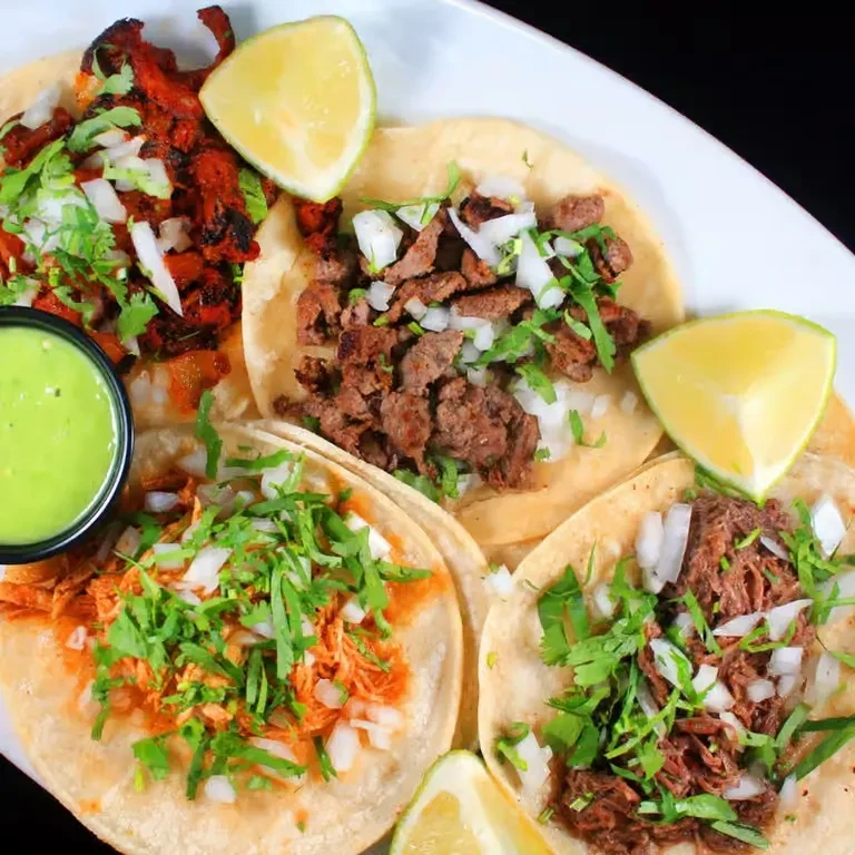 Platter of five street tacos with assorted meat, toppings, and sides.
