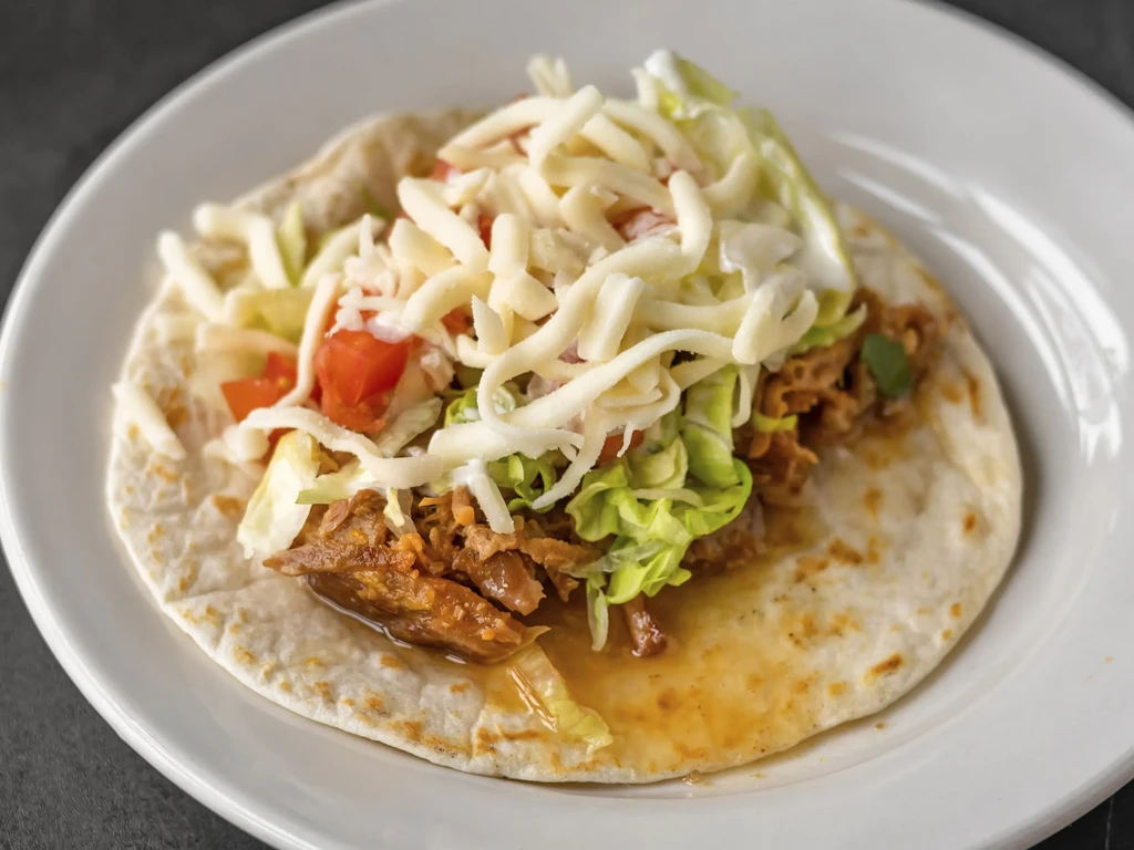 Overhead shot of a taco filled with meat, lettuce, tomato, cheese.