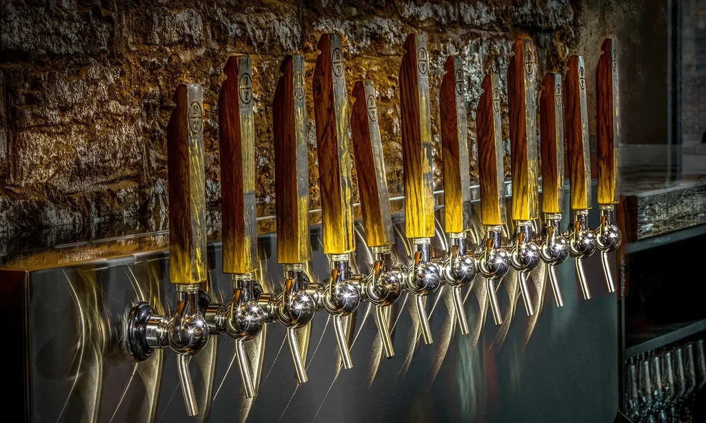 Eleven two-toned wooden beer taps on a stainless steel base.