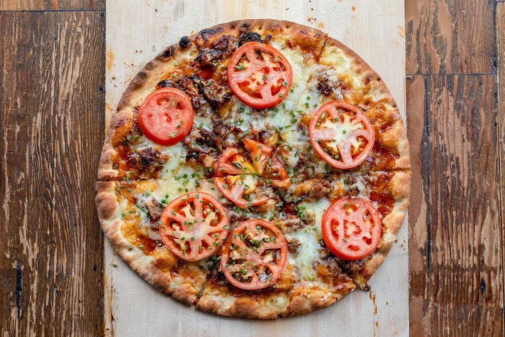 Freshly baked pizza with melted cheese, tomatoes, and chives.