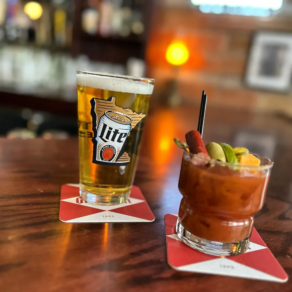 A Minnesota beer and heavily garnished Bloody Mary sit on a wooden bar.