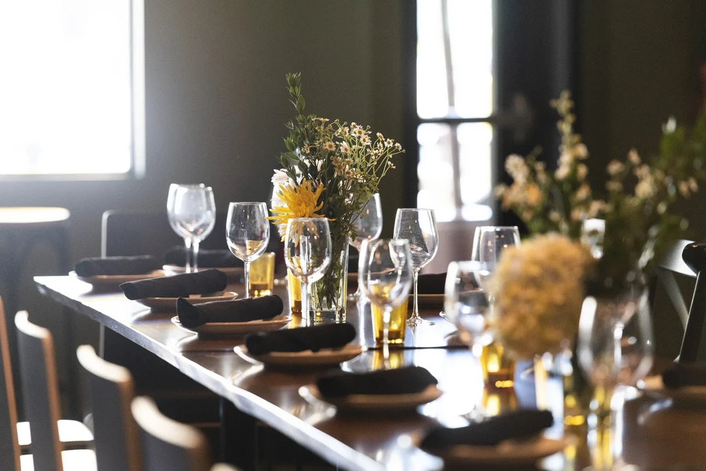 Empty dining table set for guests with floral centerpieces.