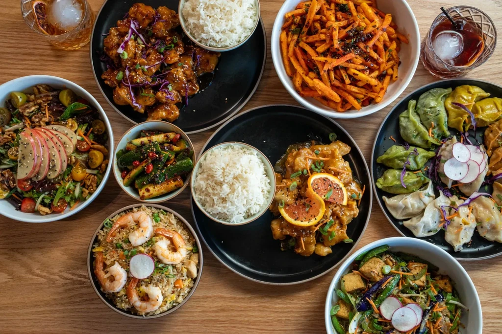 Top-down view of diverse Asian food and drinks on a wooden table.