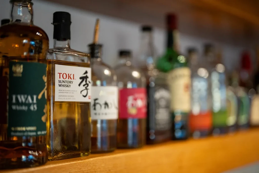 Iwai and Toki whisky bottles on a wooden shelf.