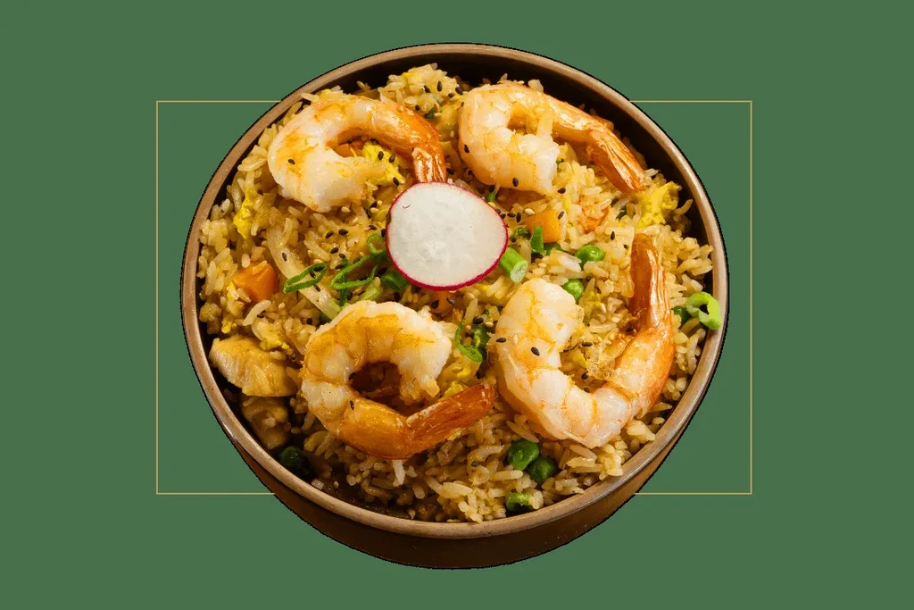 Overhead: Dark bowl of shrimp fried rice topped with shrimp and radish.