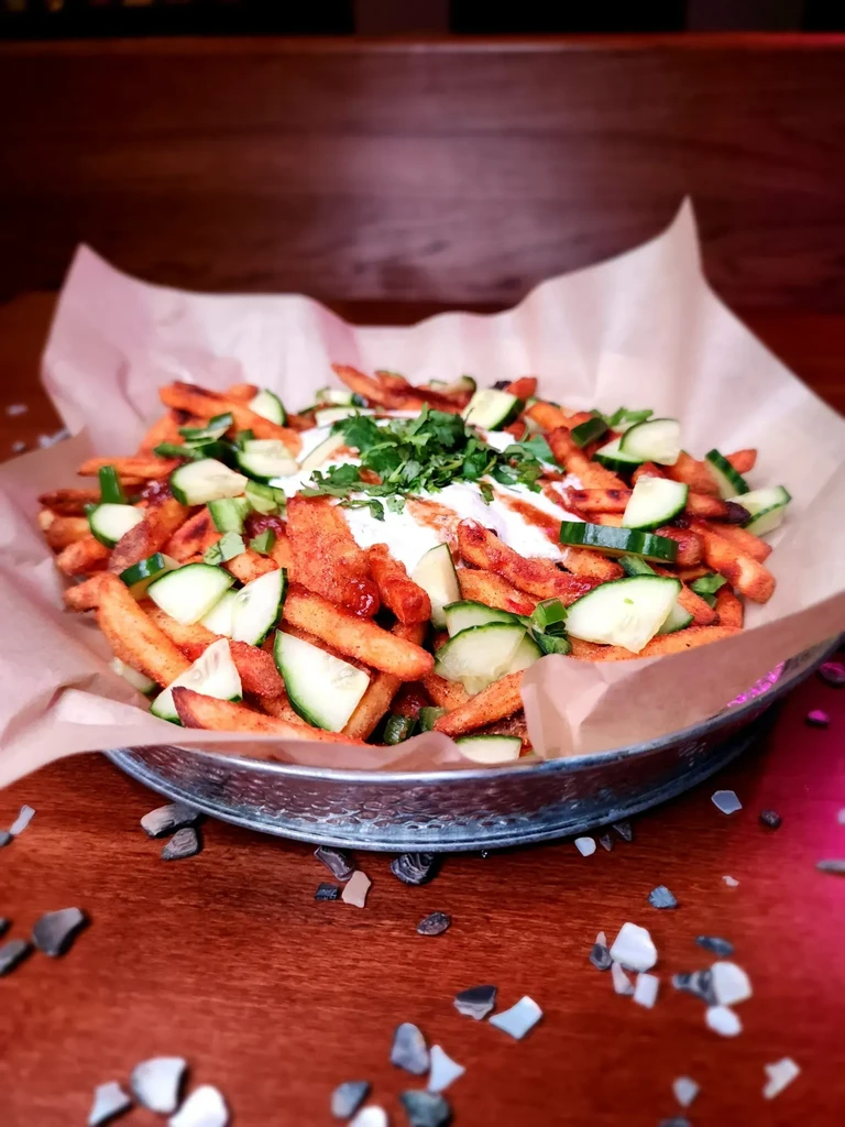 Sweet potato fries topped with cucumber, herbs, and two sauces.
