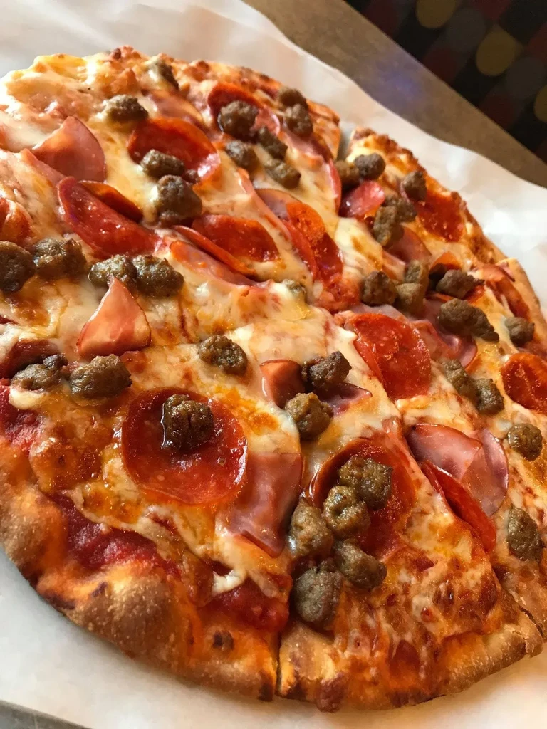 Close-up of a pizza with melted mozzarella, pepperoni, ham, and sausage.