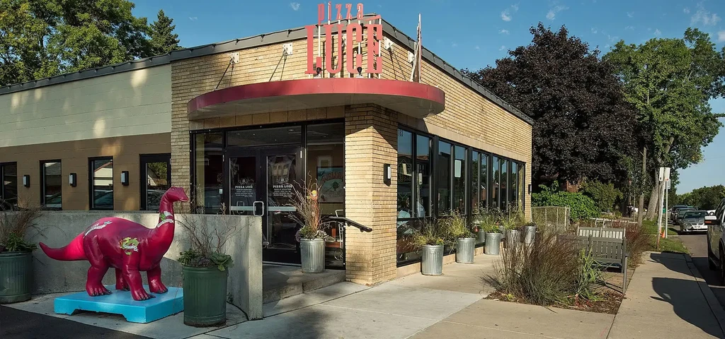 Exterior view of Pizza Luce restaurant with a large pink dinosaur statue.