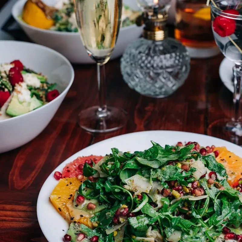 Elegant restaurant table with colorful salads, sparkling wine, and cocktails.