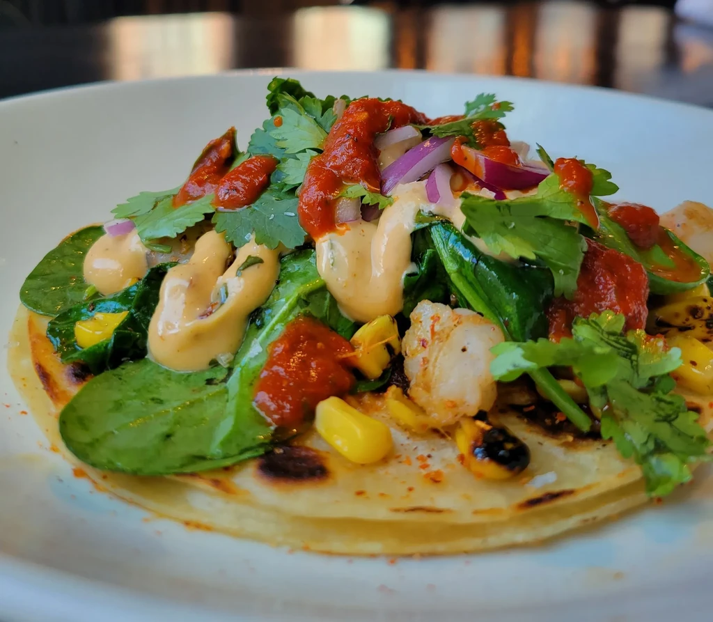 Toasted flatbread with protein, spinach, corn, red onion, cilantro, two sauces.