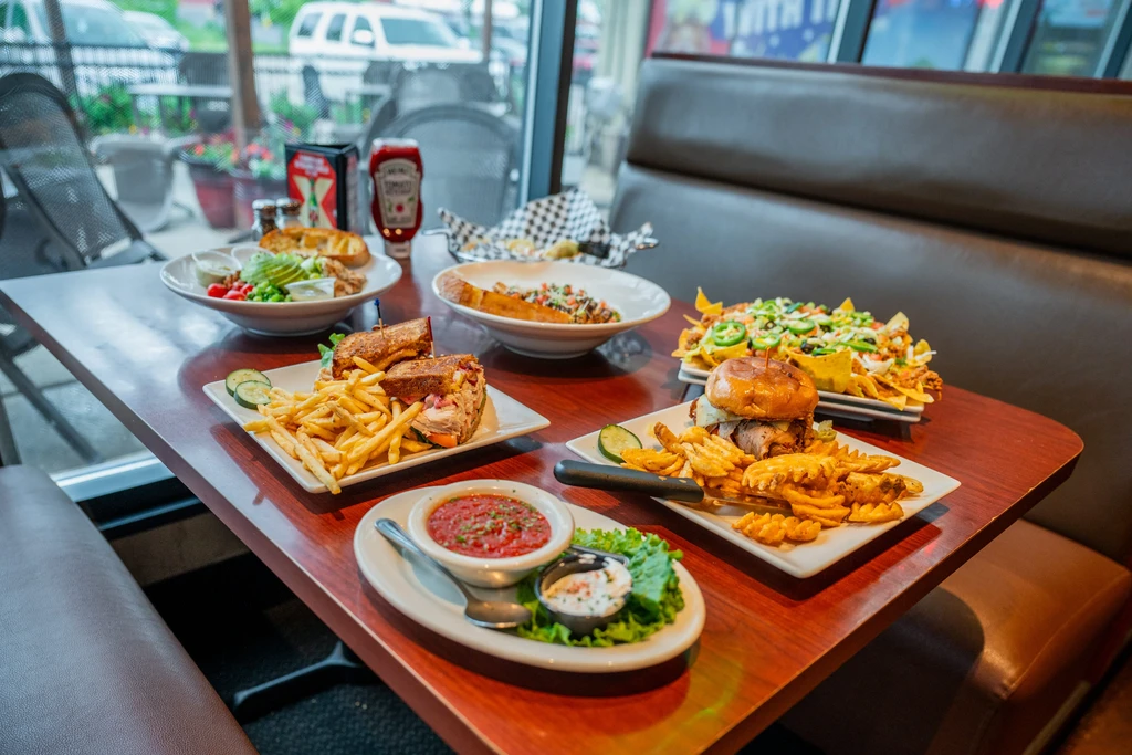 Restaurant table with a burger, nachos, salad, and various other dishes.