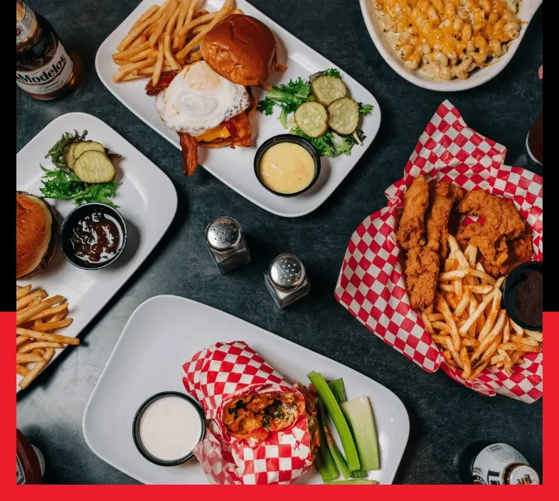 Overhead view: Burger, fried chicken, mac and cheese, wrap, and beer.