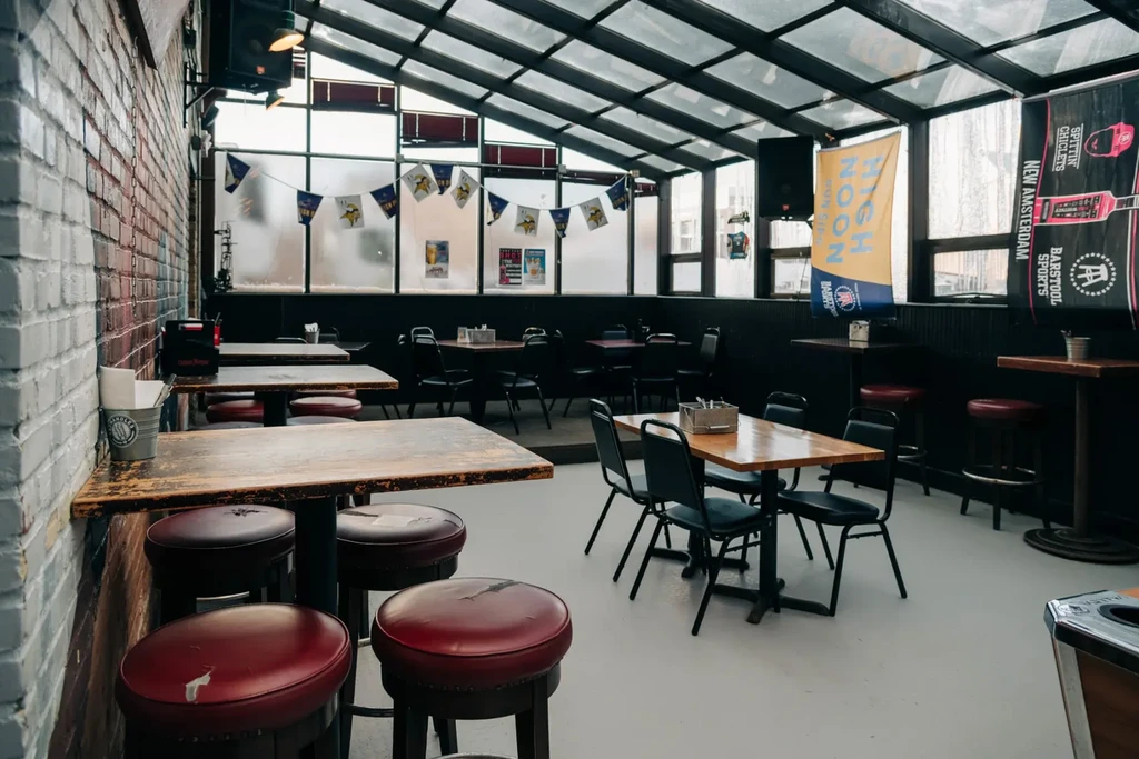 Empty, bright sports bar interior featuring high-top tables, banners, and a glass roof.