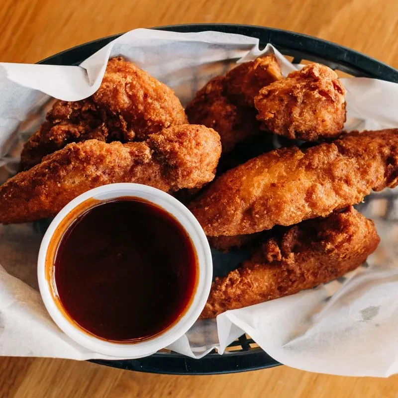 Crispy fried chicken in a basket with dipping sauce.