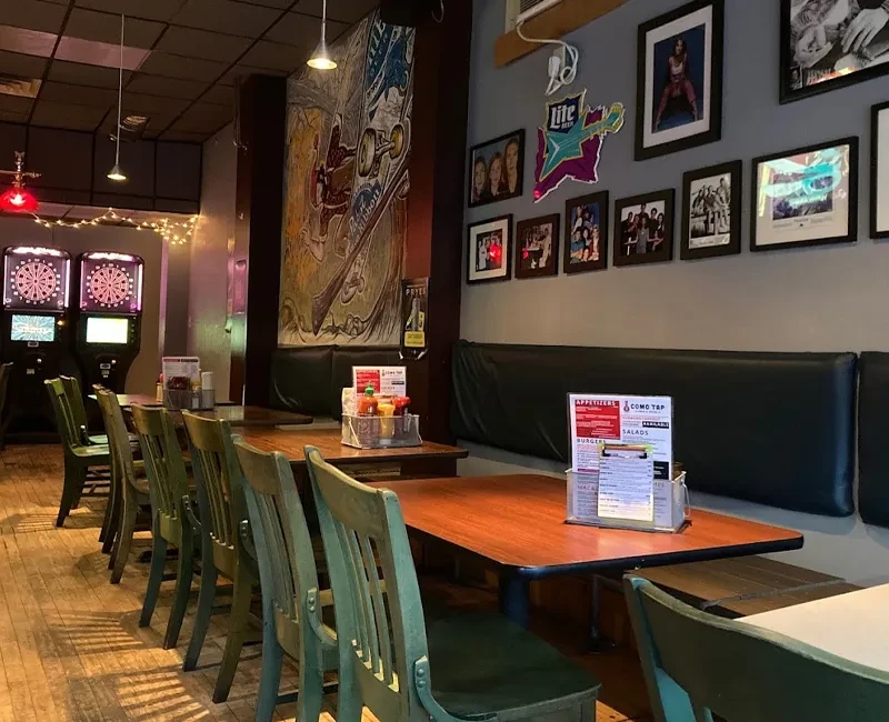 Laid-back restaurant with green chairs, band photos, dartboards, and warm lighting.