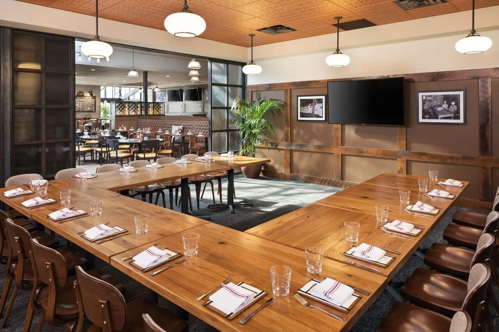 Empty, elegant restaurant interior with a set U-shaped table and tin ceiling.