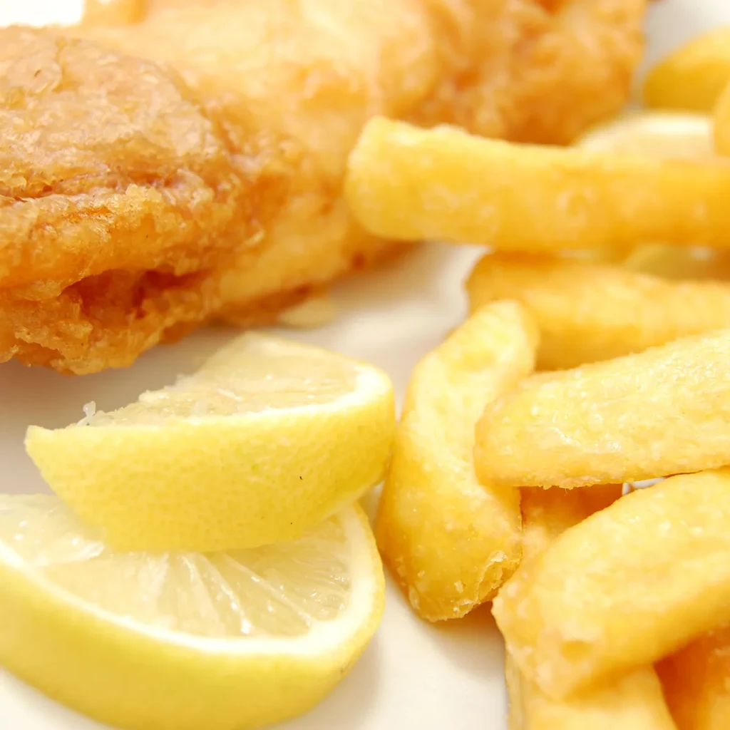 Crispy fried fish, golden fries, and two stacked lemon wedges.