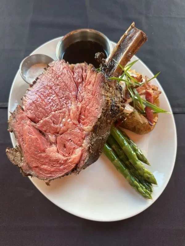 Bone-in prime rib with loaded baked potato, asparagus, gravy, and horseradish.