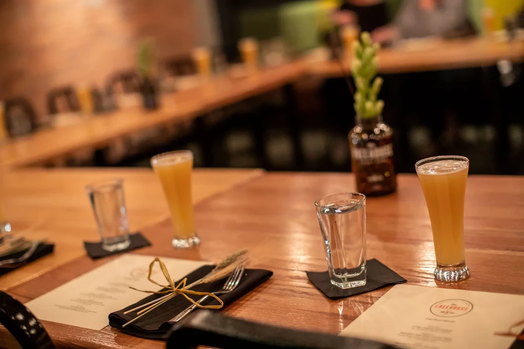Warmly lit restaurant table with beer, water, and rustic tied cutlery.