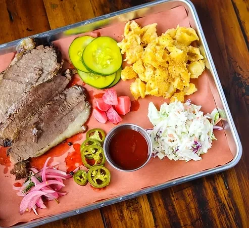 Smoked brisket platter with mac and cheese, coleslaw, and pickles.