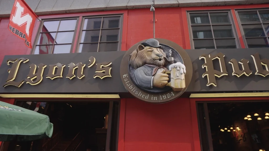 Red Lyon's Pub exterior, sign with lion mascot, Nebraska flag.