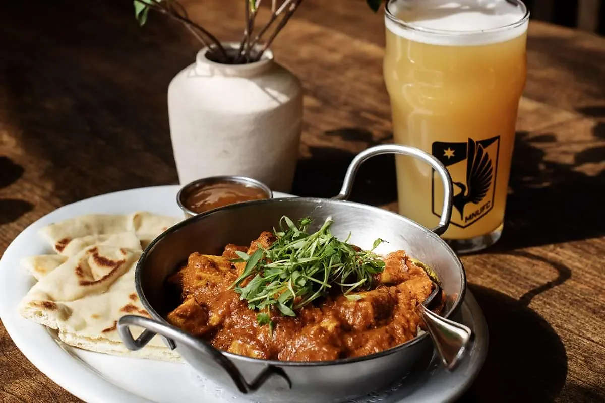Chicken tikka masala with naan and a beer on wood table