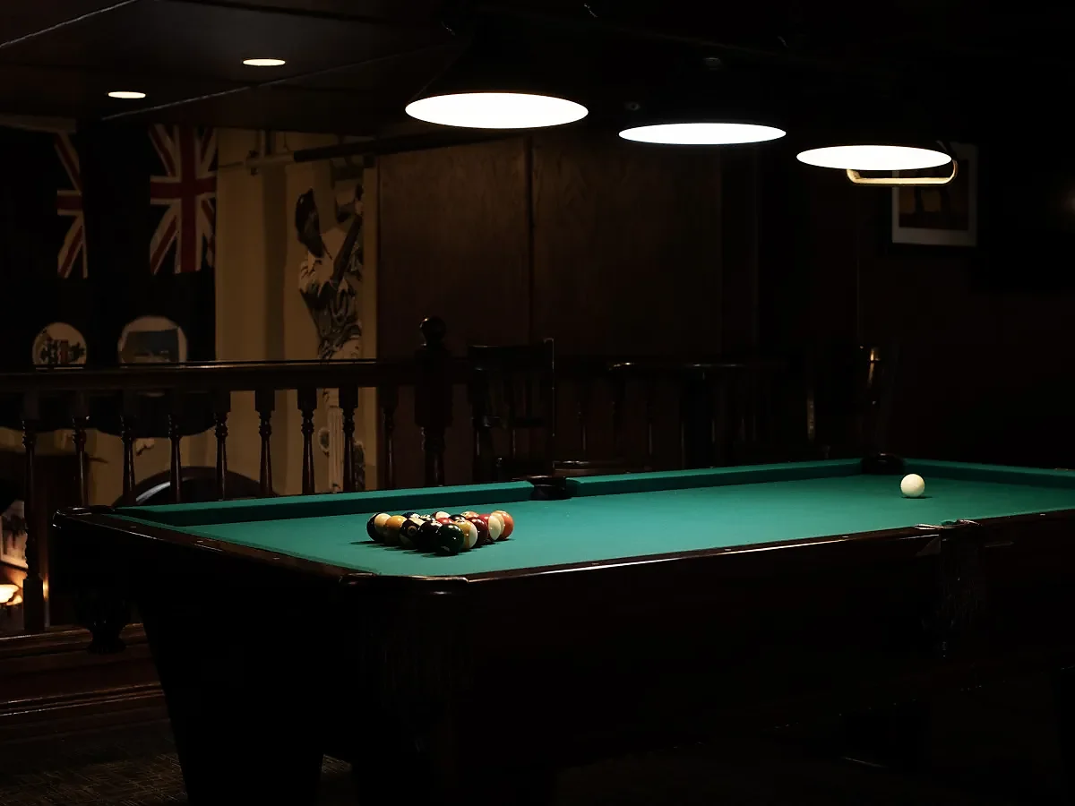 Pool table with racked balls under pendant lights and Union Jack