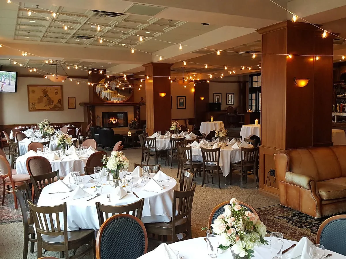 Event room with white linen tables, string lights and lit fireplace