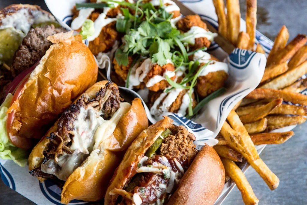 Overhead platter of sliders, fried chicken, and french fries.