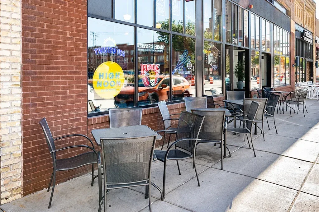 Commercial building exterior with patio, brick facade, and brand ads.