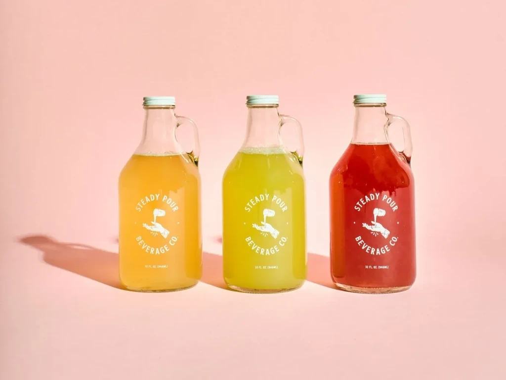 Three Steady Pour Beverage Co. bottles: yellow, green, and red.